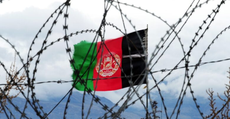 Afghan flag behind barbed wire.