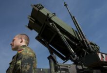 A German soldier stands to attention in front of a German Patriot missile launcher