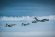 A German Air Force Airbus A400M Atlas flies in formation with four Finnish F/A-18 fighters.