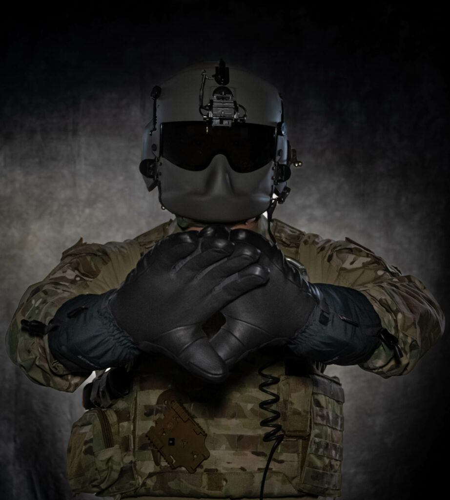 U.S. Air Force Staff Sgt. Dylan Metcalf, a 54th Helicopter Squadron flight engineer, poses with a pair of heated glove prototypes being tested by Team Minot at Minot Air Force Base, North Dakota, July 28, 2023. The 54th HS can work up to approximately 10,000 feet where temperatures can be extremely low, requiring the highest level of cold weather equipment to stay warm and offset hypothermia. (U.S. Air Force photo by Airman 1st Class Alexander Nottingham)