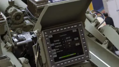 A Laser Inertial Artillery Pointing System (LINAPS) capability is seen with its screen displaying various details about its weapon's positioning (eastings, northings, height, zone, etc.). The screen has 32 buttons on its frame. Various mechanisms are seen on the back of the system. The whole unit is painted grayish green.
