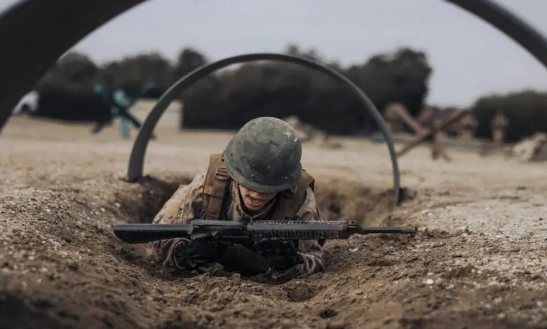 A US Marine Corps recruit crawls under an obstacle on the bayonet assault course at Marine Corps Recruit Depot San Diego, California