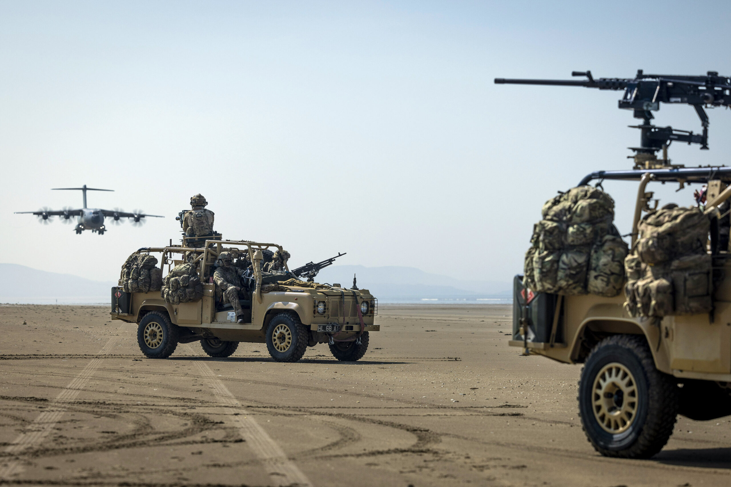 Pictured: Members of the Pathfinder Platoon, 16 Air Assault brigade provide all round protection in RWMIK’s whilst the RAF ATLAS C.1 performs touch & go landings at Pembrey Sands beach. The reconnaissance troops who are first in for the British Army’s Global Response Force have tested how they can insert behind enemy lines in aircraft landing on impromptu runways. Mounted in heavily armed RWMIK patrol vehicles, troops from Pathfinders - the advance force for 16 Air Assault Brigade - were delivered onto Pembrey Sands in southwest Wales from an RAF ATLAS C.1 (A400M) aircraft. With the beach’s vast expanse exposed at low tide, the aircraft swooped in to land on an area that Pathfinders had identified as firm and large enough to land on and marked for the pilots. With its four engines still running, the aircraft dropped its back ramp for the vehicles to drive off, and then took off after being on the ground for the shortest possible time. The rising tide covered all evidence that the aircraft had ever been there, while Pathfinders quickly moved off into the Welsh countryside. In military jargon this is known as a Rapid Air Landing (RAL) on a Temporary Landing Zone (TLZ). For the aircraft of the RAF’s Air Mobility Force to be able to conduct these operations gives greater flexibility in how troops can be delivered on to an operation, in a more covert way and without being restricted to permanent runways that can be defended by enemy troops. Pathfinders are trained to infiltrate behind enemy lines and work in small patrols, either in vehicles or on foot, to find and relay vital information back to assist mission planning. A key role is identifying drop zones and landing zones where the main body of troops can be parachuted or landed by helicopter or aircraft. Alongside their primary reconnaissance role, Pathfinders provide a highly mobile strike force to support 16 Air Assault Bde missions by carrying out raids on high value targets or feints in supp