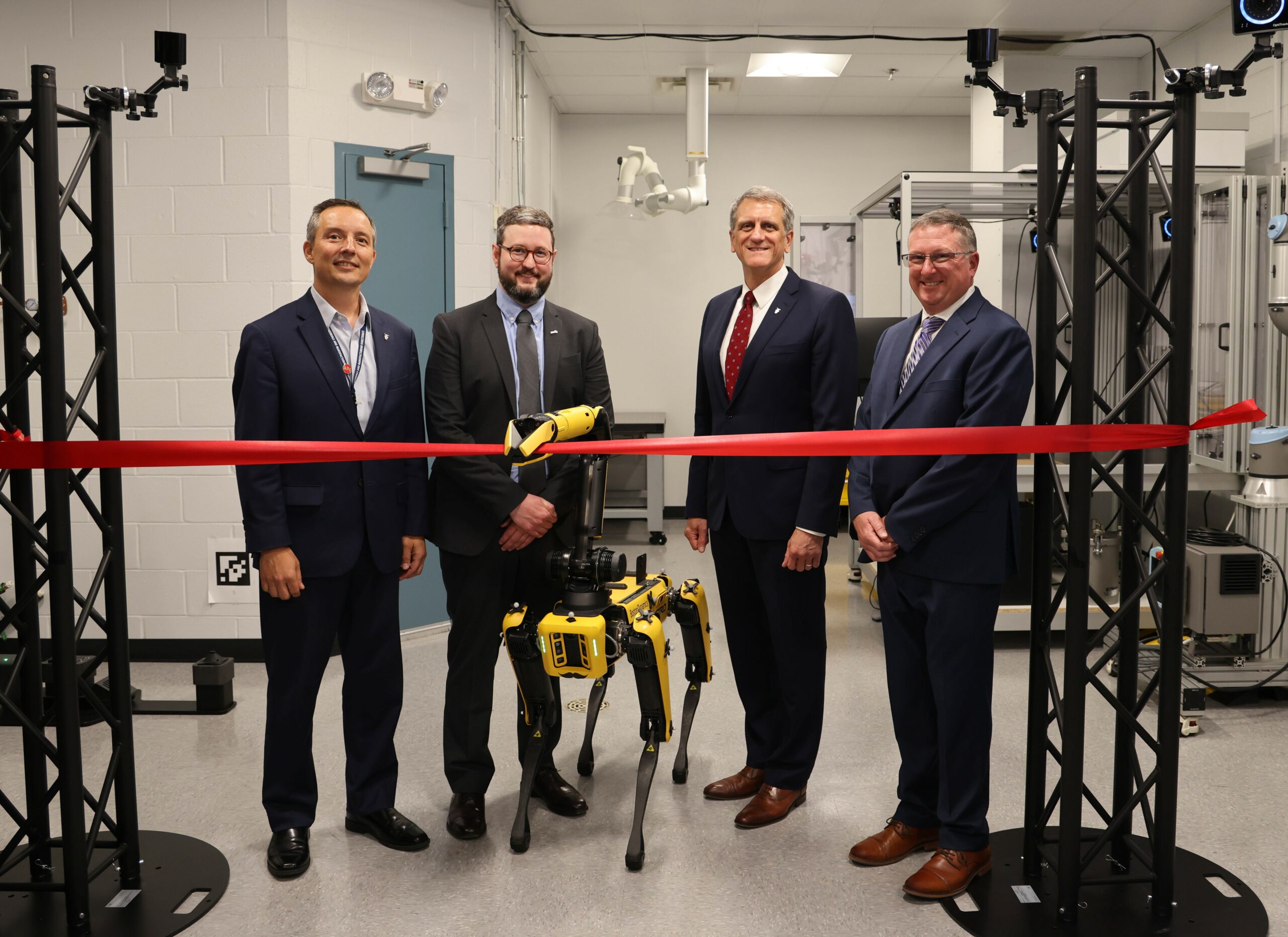 From left: Darrell Phillipson, director, Air Force Research Laboratory, or AFRL, Materials and Manufacturing Directorate; Dr. Sean Donegan, Digital Manufacturing Research Team lead; Timothy Sakulich, AFRL executive director; and Dr. Charles Ormsby, Manufacturing, Industrial Technologies and Energy division chief observe as Boston Dynamics robot Astro cuts a ceremonial ribbon, officially opening the new Collaborative Automation for Manufacturing Systems Laboratory at Wright-Patterson Air Force Base, July 23, 2024. (U.S. Air Force photo / Sarah Perez)