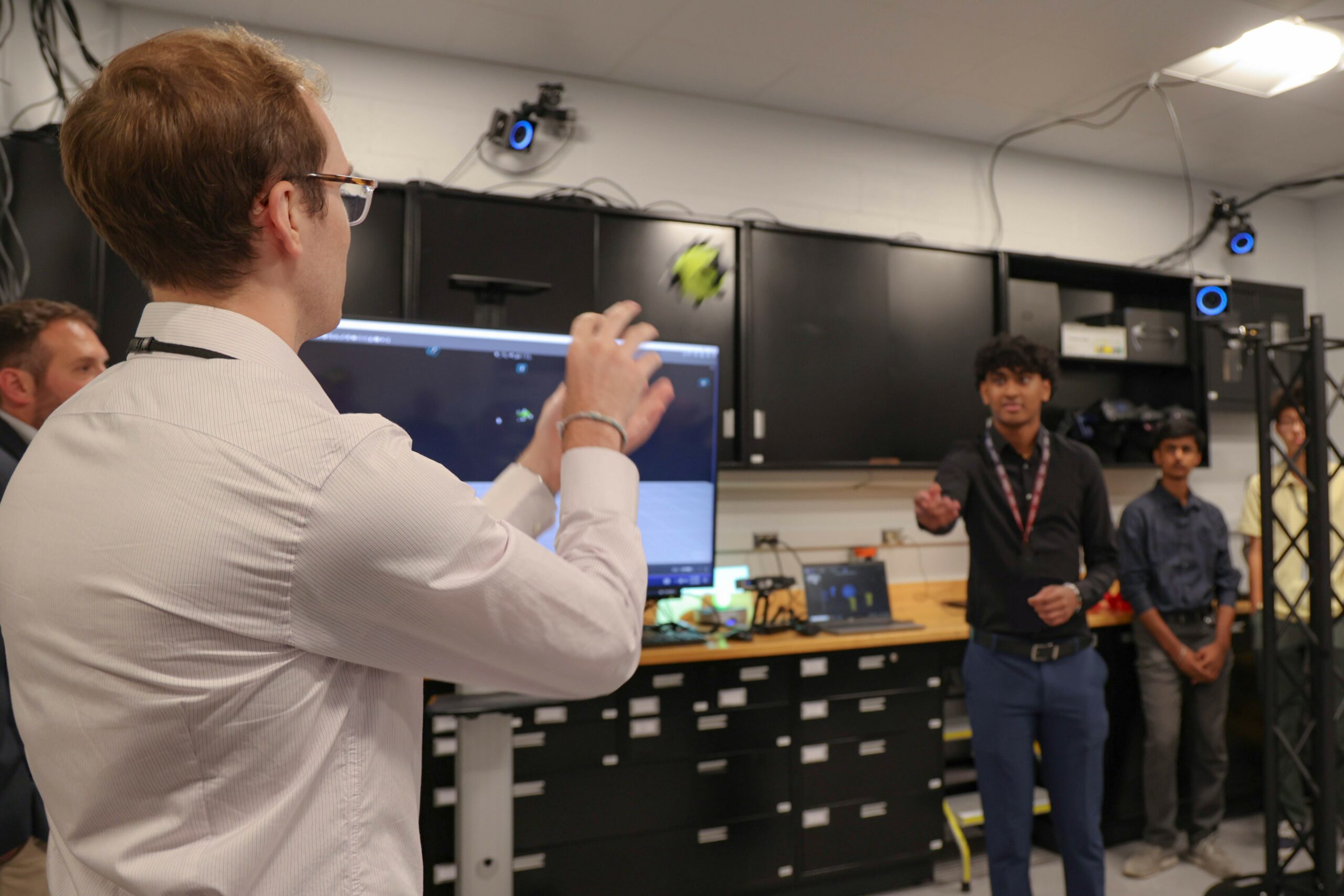 From left: Andrew Bowman, on-site researcher with the Air Force Research Laboratory’s Digital Manufacturing Research Team, or DMRT, and Yash Kakade, a DMRT summer intern, demonstrate the motion capture system in the newly opened Collaborative Automation for Manufacturing Systems Laboratory at Wright-Patterson Air Force Base following a ribbon-cutting ceremony, July 23, 2024. (U.S. Air Force photo / Sarah Perez)