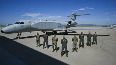 U.S. Air Force Chief Master Sgt. Andrew Small, 55th Wing command chief, Col. Mark Howard, 55th Wing commander, Lt. Gen. Thomas Hensley, 16th Air Force commander, Gen. Ken Wilsbach, commander of Air Combat Command, Chief Master Sgt. Robert Hopkins, 16th Air Force command chief, Lt. Col. Stephen Koether, 645th Aeronautical Systems Squadron Detachment 1 commander, Lt. Col. Jacob Arndt, 645 AESS Det 1 director of operations, and Maj. Mark Busby, 645 AESS Det 1 director of test, pose in front of aircraft 19-5591, ACC’s first EA-37B Compass Call delivered to Davis-Monthan AFB, Arizona, on Aug. 23, 2024. (U.S. Air Force photo by Senior Airman Paige Weldon)