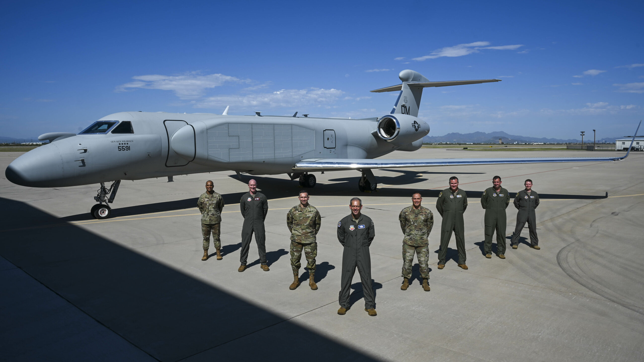 U.S. Air Force Chief Master Sgt. Andrew Small, 55th Wing command chief, Col. Mark Howard, 55th Wing commander, Lt. Gen. Thomas Hensley, 16th Air Force commander, Gen. Ken Wilsbach, commander of Air Combat Command, Chief Master Sgt. Robert Hopkins, 16th Air Force command chief, Lt. Col. Stephen Koether, 645th Aeronautical Systems Squadron Detachment 1 commander, Lt. Col. Jacob Arndt, 645 AESS Det 1 director of operations, and Maj. Mark Busby, 645 AESS Det 1 director of test, pose in front of aircraft 19-5591, ACC’s first EA-37B Compass Call delivered to Davis-Monthan AFB, Arizona, on Aug. 23, 2024. (U.S. Air Force photo by Senior Airman Paige Weldon)