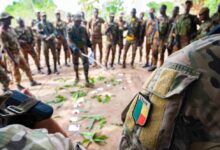 A Beninese platoon lieutenant uses a sand table diagram to discuss squad assignments.