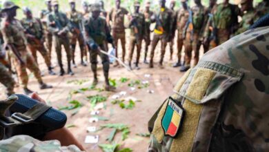 A Beninese platoon lieutenant uses a sand table diagram to discuss squad assignments.