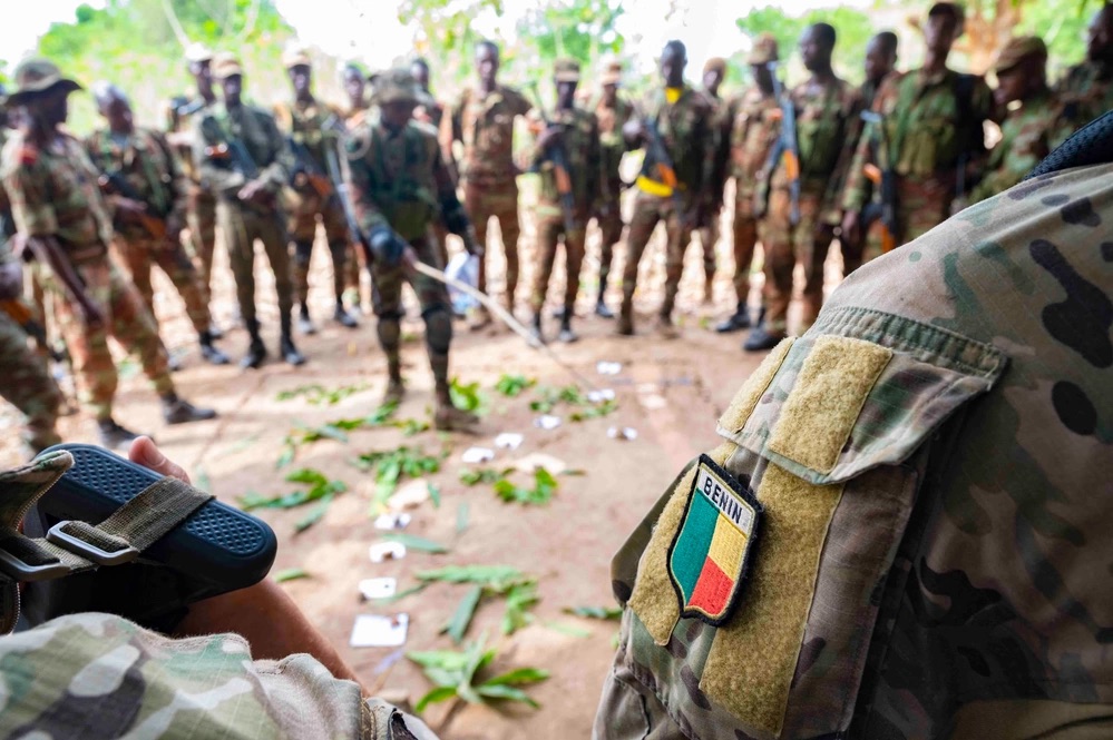 A Beninese platoon lieutenant uses a sand table diagram to discuss squad assignments.