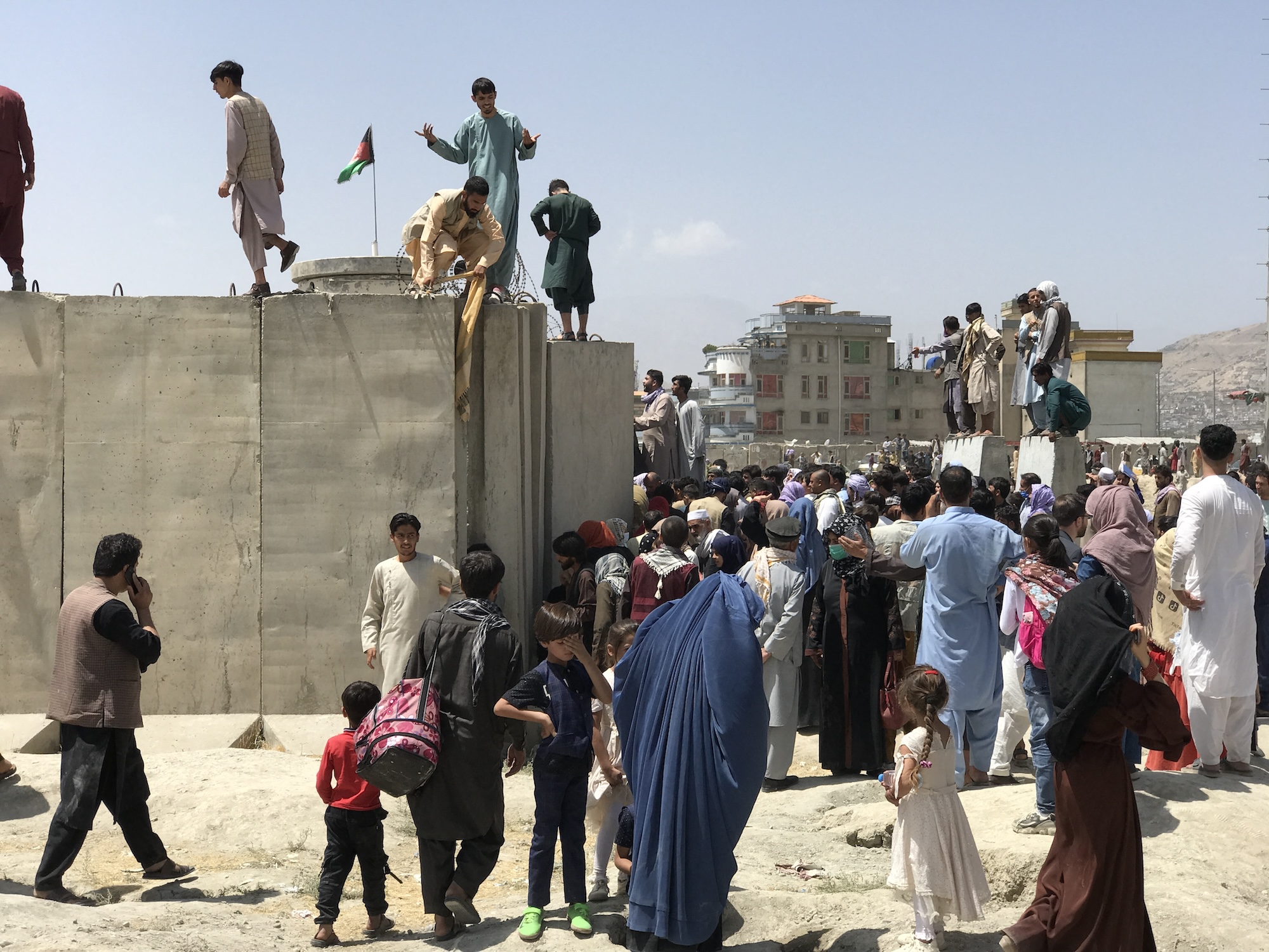 People struggle to cross the boundary wall of Hamid Karzai International Airport to flee the country after rumors that foreign countries are evacuating people even without visas, after the Taliban over run of Kabul, Afghanistan