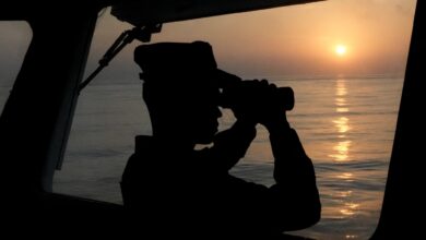 A law enforcer observes on the vessel "China Coast Guard (CCG) 3502" in the South China Sea, May 12, 2024