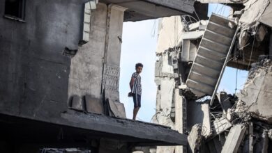 A young Palestinian boy stands near a building destroyed by an Israeli airstrike in the Nuseirat refugee camp in central Gaza Strip on August 23, 2024