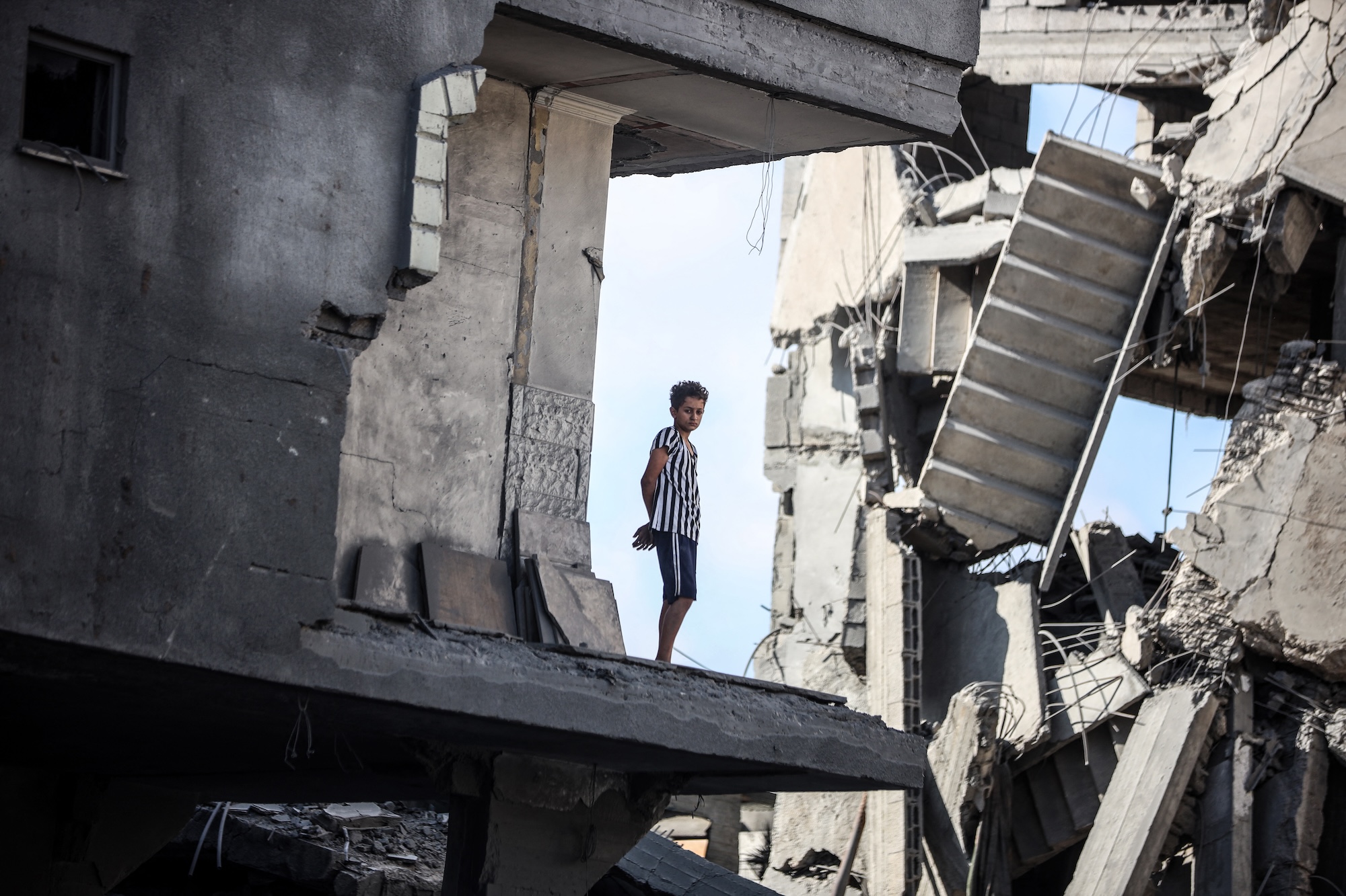 A young Palestinian boy stands near a building destroyed by an Israeli airstrike in the Nuseirat refugee camp in central Gaza Strip on August 23, 2024