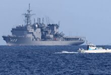 A JMSDF minesweeper vessel and two fishing boats sailing on a blue ocean