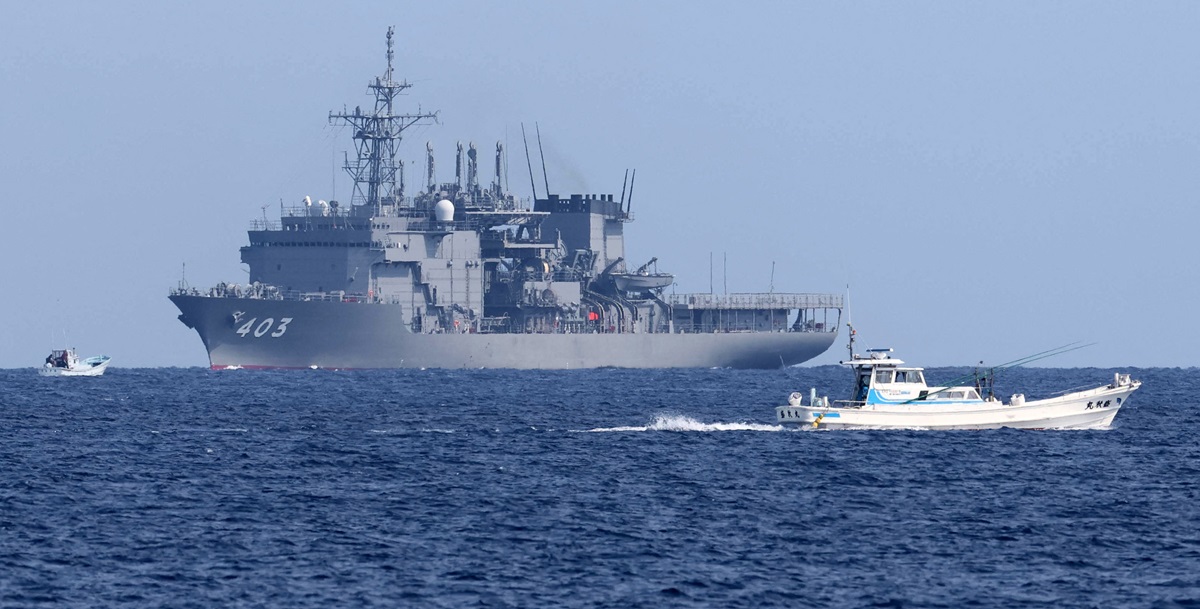 A JMSDF minesweeper vessel and two fishing boats sailing on a blue ocean