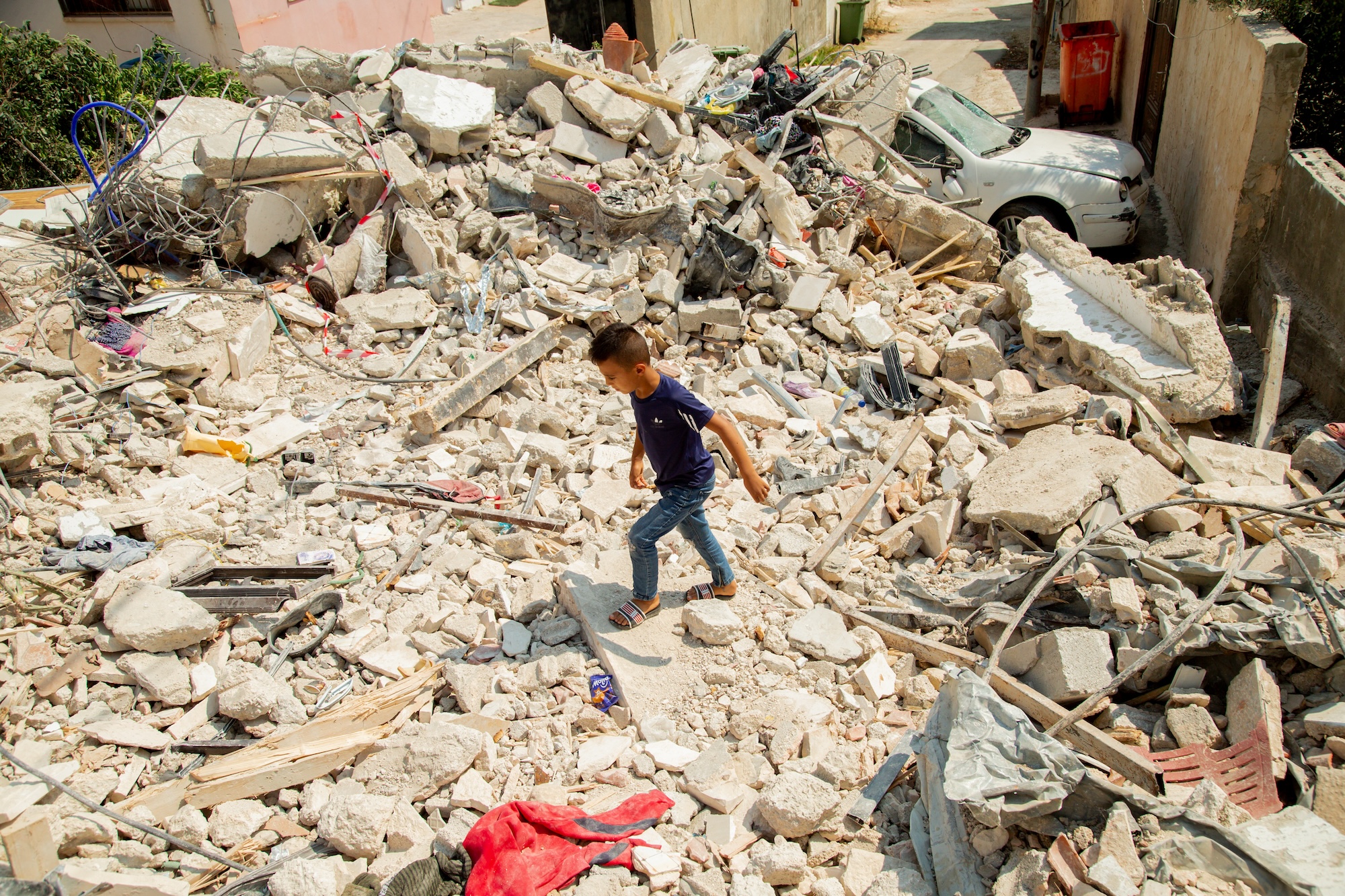 A Palestinian boy walks among houses that were destroyed in Israeli air strikes in Jenin refugee camp in the West Bank