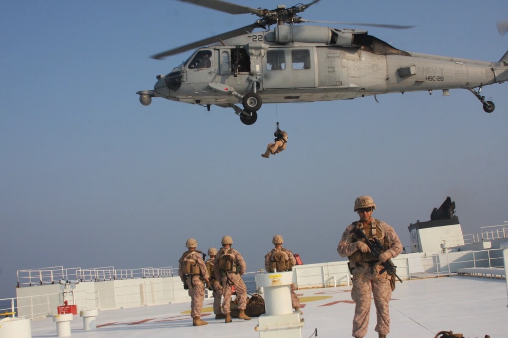 Marines assigned to Fleet Anti-Terrorism Security Team, Central Command prepare to be extracted by a Navy MH-60S Seahawk, attached to Helicopter Sea Combat Squadron 26 (HSC-26) from the Arc Liberty, a Military Sealift Command time chartered vessel, after providing security during a Strait of Hormuz transit