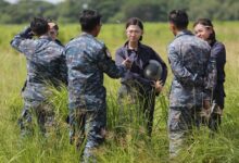 Three female student pilots from the Royal Thai Air Force listening to their instructors on the field