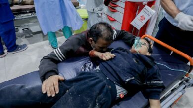 A man holds onto an injured child on a stretcher at Al-Awda Hospital in Al-Nuseirat, Gaza, on October 28