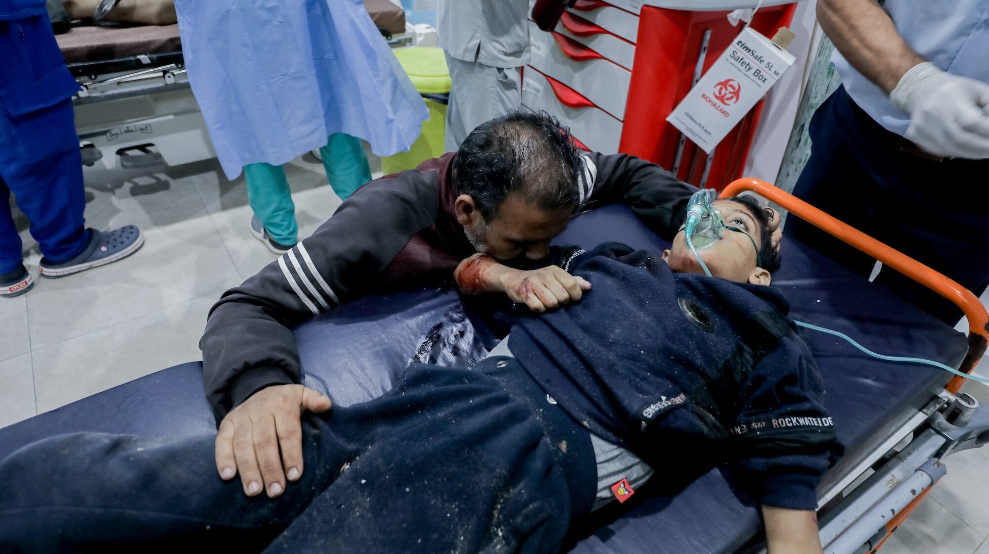 A man holds onto an injured child on a stretcher at Al-Awda Hospital in Al-Nuseirat, Gaza, on October 28