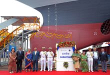 Indian Navy officials pose in front of the Samarthak multipurpose vessel