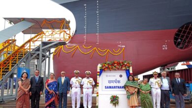 Indian Navy officials pose in front of the Samarthak multipurpose vessel