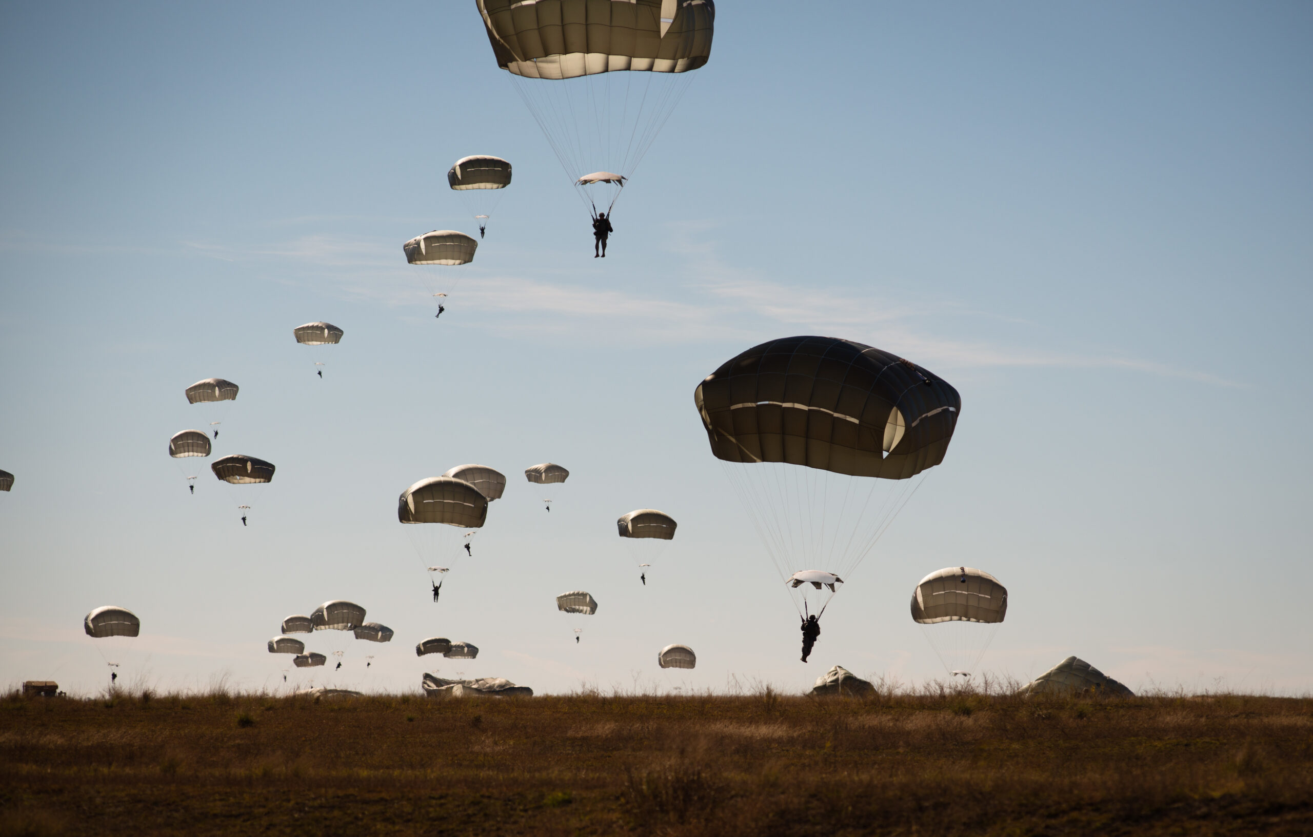 Paratroopers float to earth as part of the re-invigorated Saturday Proficiency Jump Program, Nov. 21, 2015, on Sicily Drop Zone. The once popular program was restarted in October to allow paratroopers to build additional proficiency and confidence for airborne operations. In November the program continued to build momentum with an additional 150 jumpers. Families and friends gathered on Sicily Drop Zone to watch the daytime spectacle and share in the unique U.S. Army paratrooper experience. (U.S. Army photo by Staff Sgt. Charles Crail, XVIII Airborne Corps/Released)