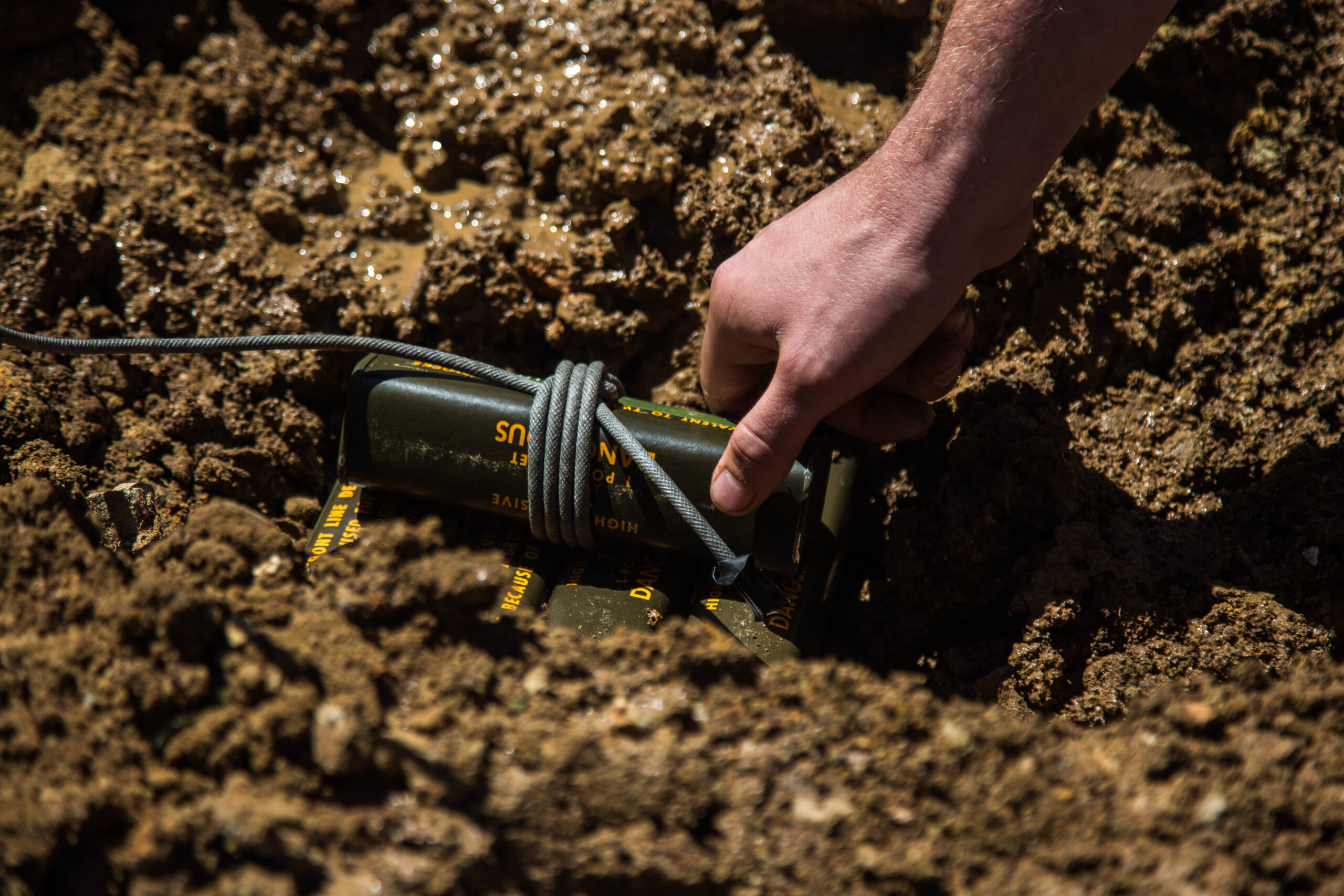 A U.S. Marine with 1st Explosive Ordnance Disposal Company, 7th Engineer Support Battalion, 1st Marine Logistics Group, places a charge of trinitrotoluene (TNT) in a muddy portion of the ground during the Post-Blast Analysis Course at Camp Pendleton, Calif., April 11, 2018. To show how terrain effects the outcome of craters explosive chargers are placed in different areas. This Includes dry packed dirt, loose dirt, and mud. (U.S. Marine Corps Photo by Lance Cpl. Quentarius Johnson)