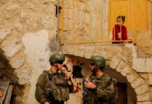 A child watches as Israeli soldiers secure the area during a tour of Hebronís old city in the West Bank