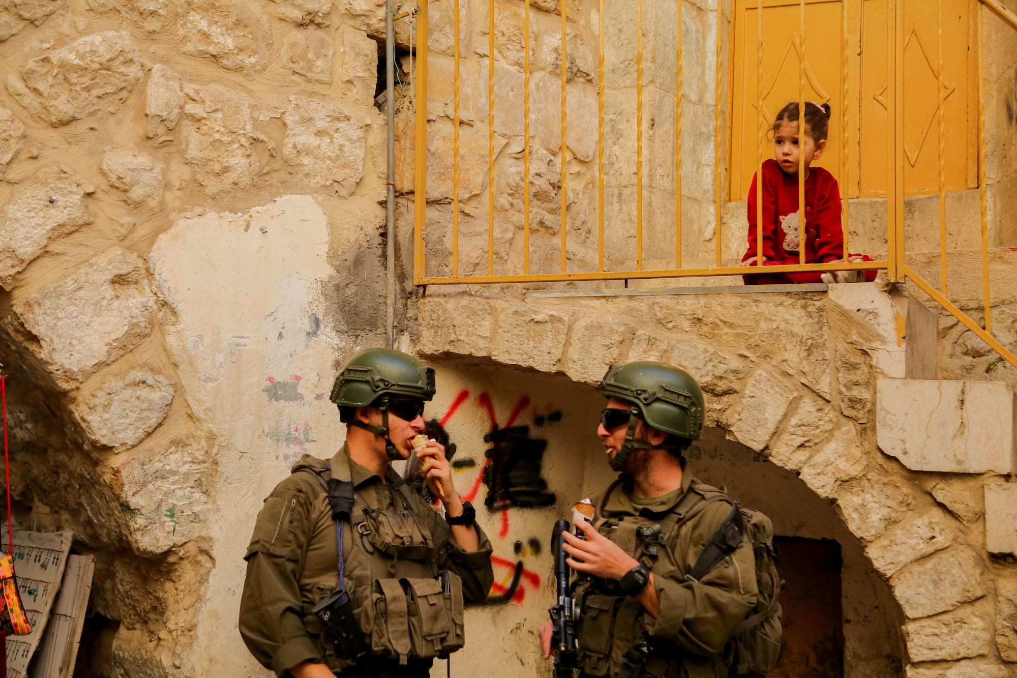 A child watches as Israeli soldiers secure the area during a tour of Hebronís old city in the West Bank