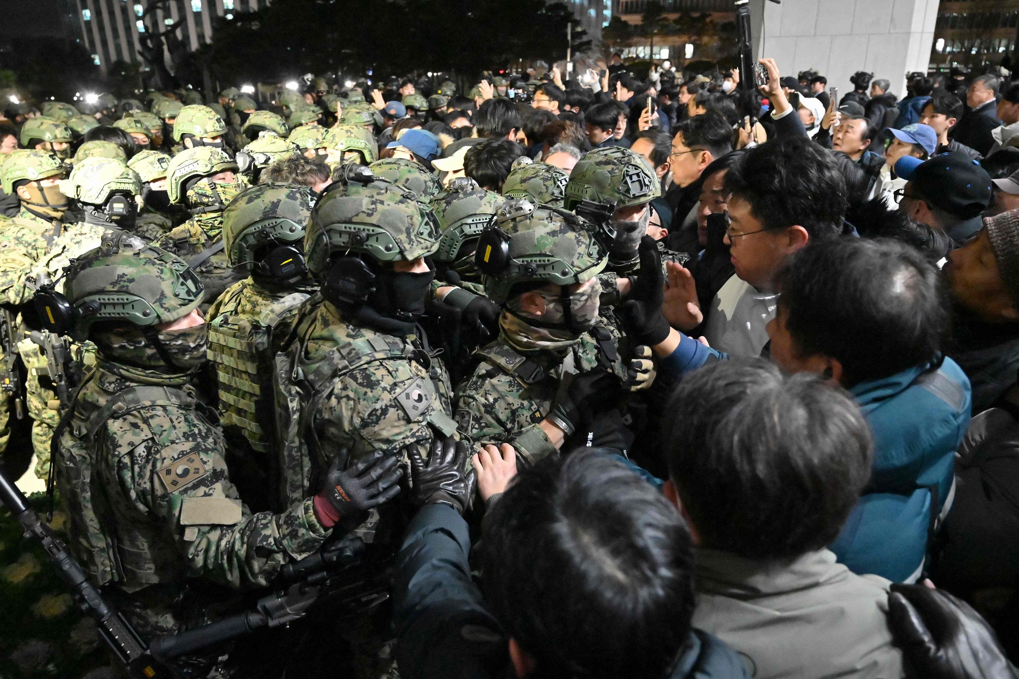 Soldiers try to enter the National Assembly building in Seoul on December 4 2024, after South Korea President Yoon Suk Yeol declared martial law. South Korea's President Yoon Suk Yeol on December 3 declared martial law, accusing the opposition of being "anti-state forces" and saying he was acting to protect the country from "threats" posed by the North. (Photo by Jung Yeon-je / AFP)