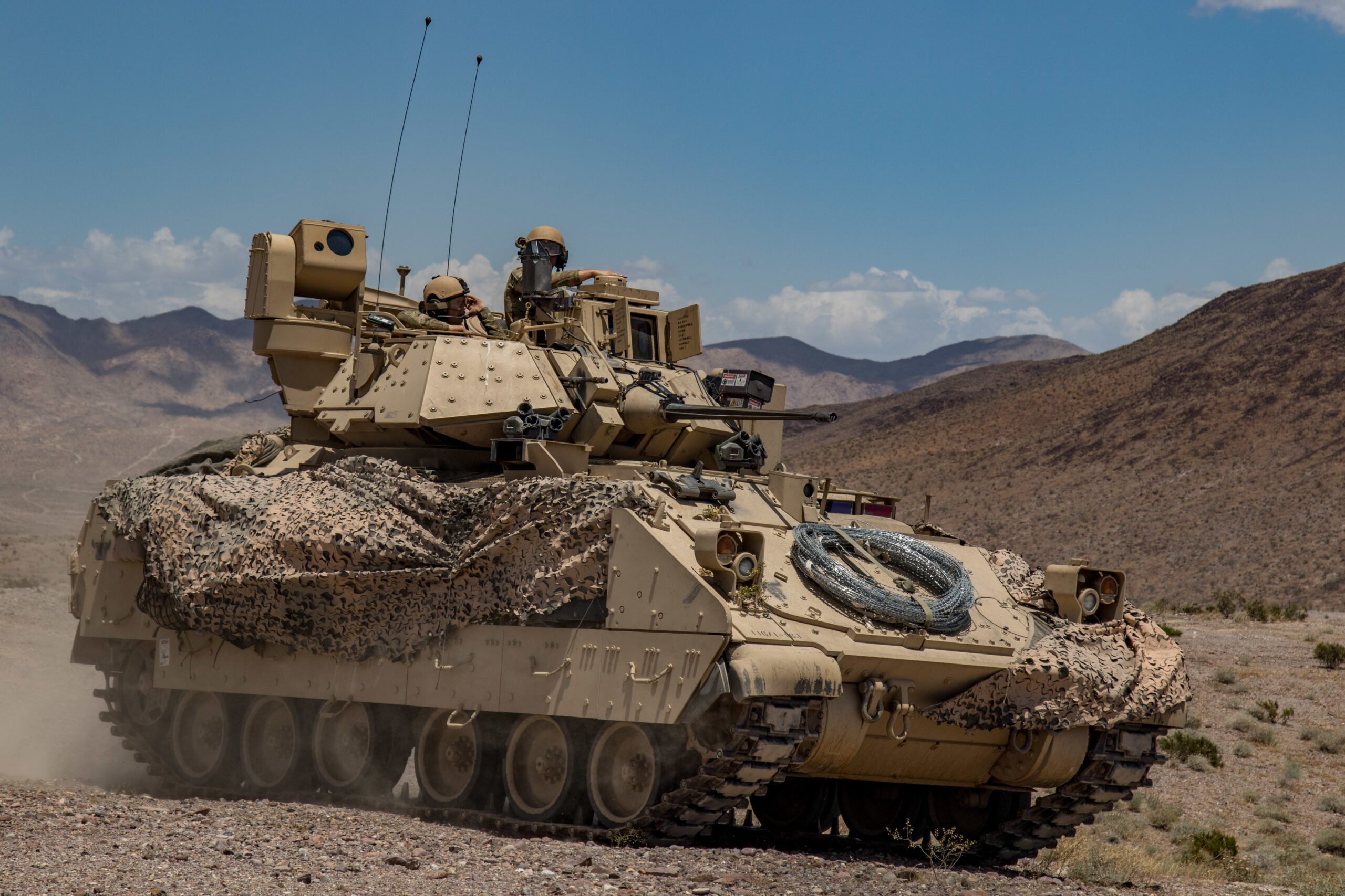 Soldiers from 1st Battalion, 163rd Cavalry Regiment, Montana Army National Guard, push on in their Bradley Fighting Vehicle during a defensive attack training exercise at the National Training Center (NTC) in Fort Irwin, Calif., June 1, 2019. A month-long NTC Rotation provides more than 4,000 service members from 31 states, including units from 13 National Guard states and territories, with realistic training to enhance their combat, support and sustainment capabilities. (Photo by: Cpl. Alisha Grezlik, 115th Mobile Public Affairs Detachment)