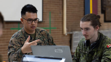 U.S. Marine Corps Cpl. Miles Young (left), data systems administrator, Defensive Cyberspace Operations, Company A, 6th Communication Battalion, Marine Forces Reserve, discusses his network hacking plan with a Canadian Army service member during Cyber Harmony 24 at The Royal Montreal Regiment, Quebec, Canada, April 28, 2024. This exercise allowed Reserve Marines to integrate with their active duty counterparts and joint partners to help develop practices in defense against cyber attacks.