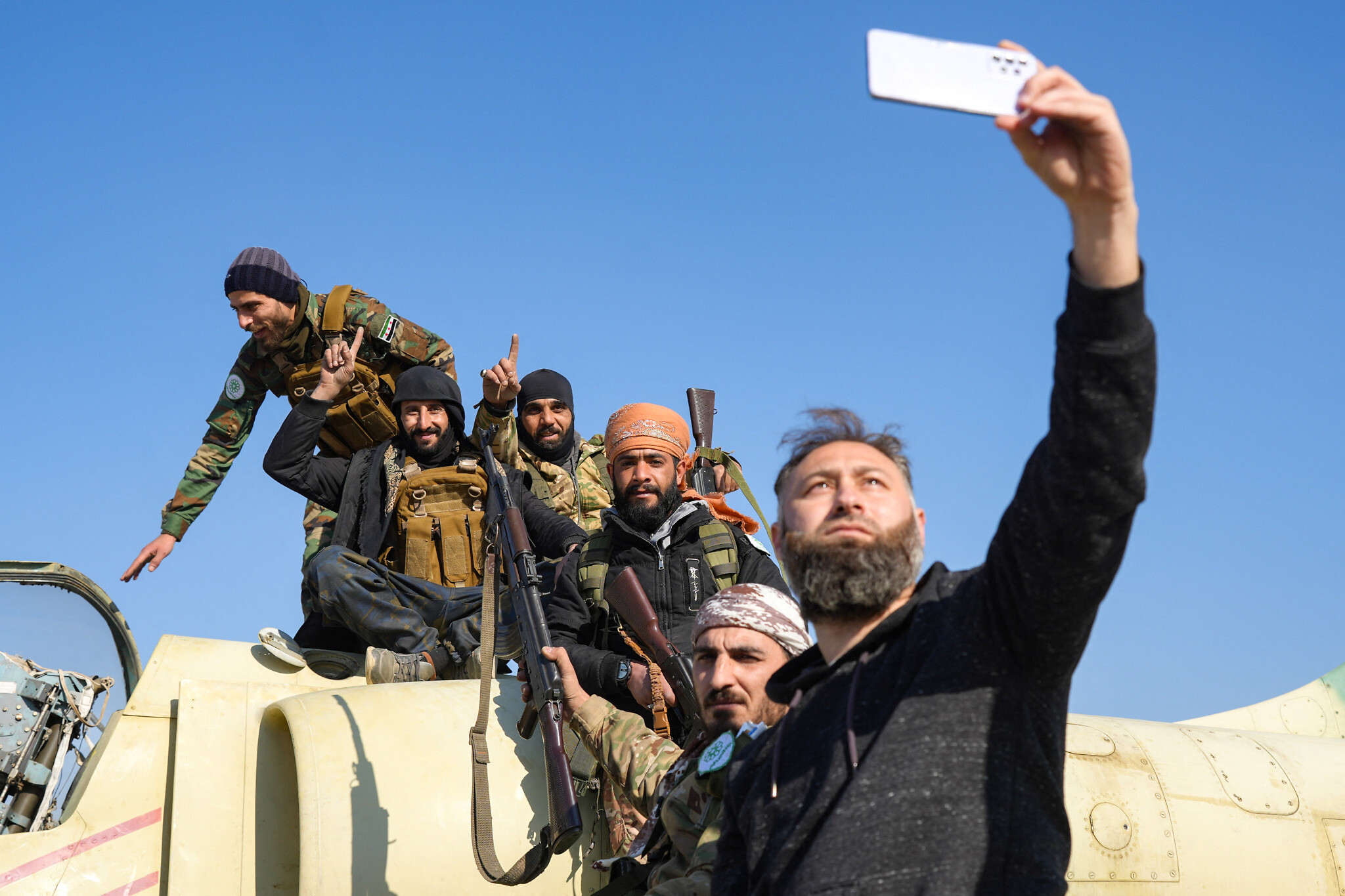 Anti-government fighters pose for a "selfie" picture on a Syrian regime military aircraft at the Kweyris military airfield in the eastern part of Aleppo province on December 3, 2024. (Rami al Sayed/AFP)