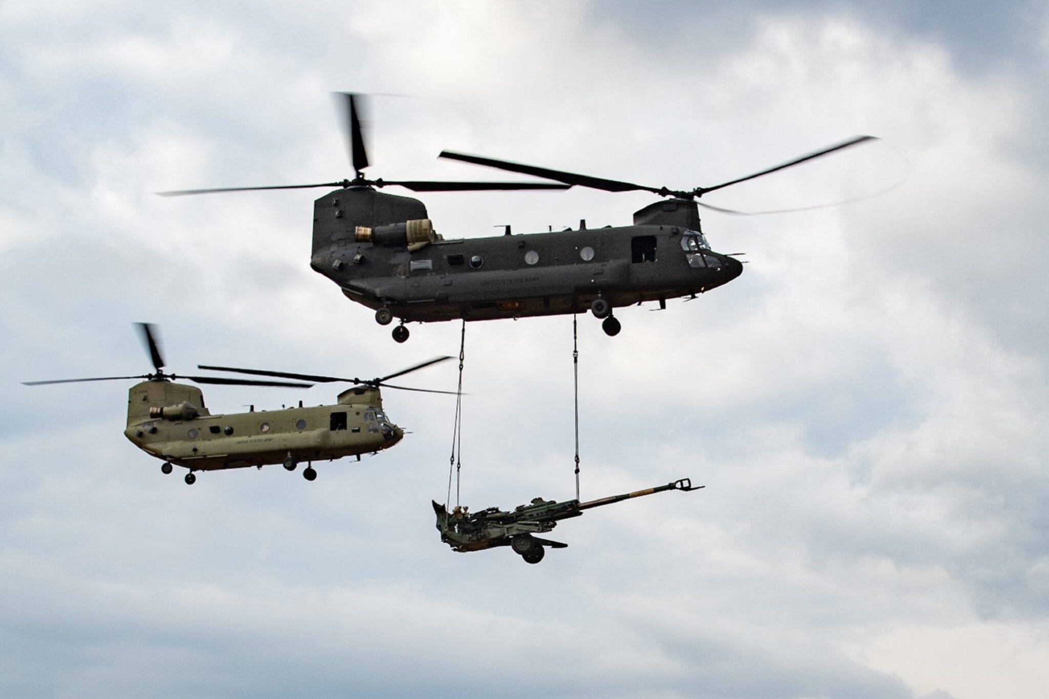 A US Army CH-47F Block II Chinook conducts a sling load test alongside a CH-47F Block I aircraft