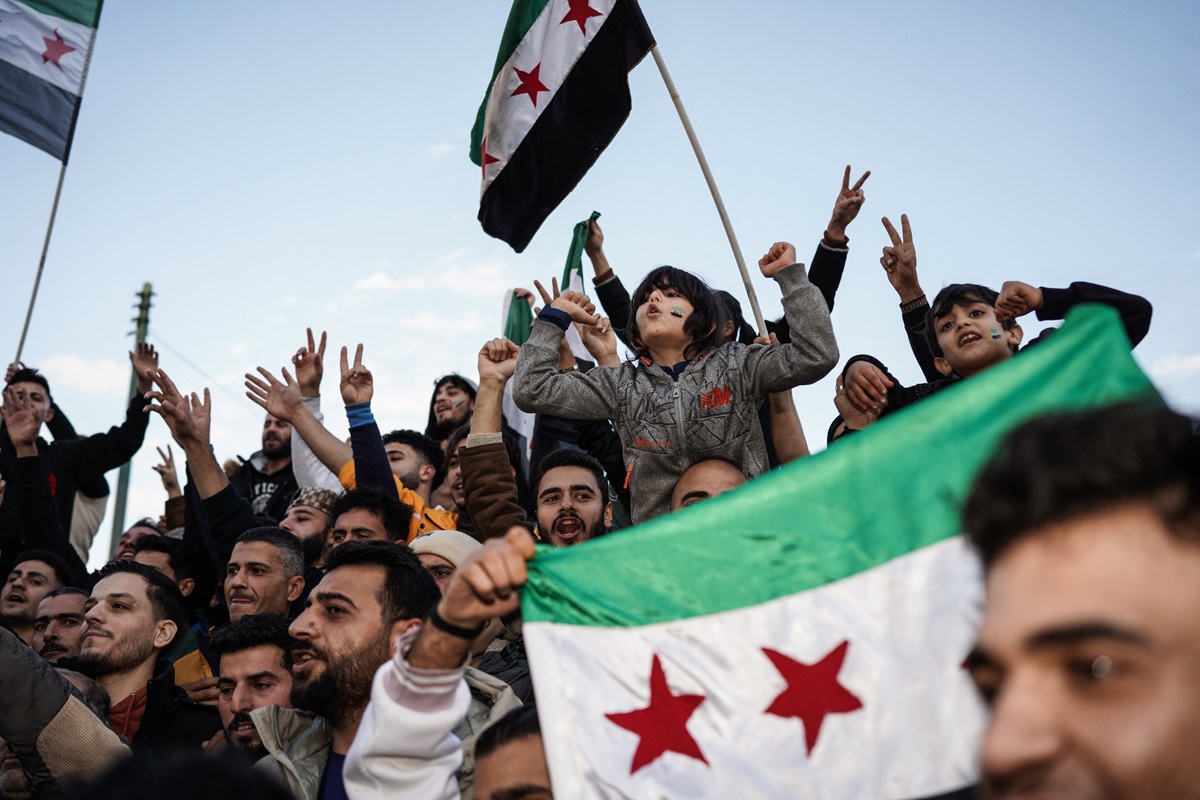 Syrians living in Athens chant slogans as they gather in Syntagma Square to celebrate the overthrow of the 61-year Ba'ath Party rule in Syria with the Syrian opposition's 'revolution flag,' following the collapse of regime control in the capital, Damascus, on Sunday, December 8, 2024, in Greece. (Photo by Nick Paleologos / SOOC / SOOC via AFP)