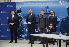 Polish defense ministry and industry leaders standing in front of the Polish Navy's Ratownik rescue ship concept design