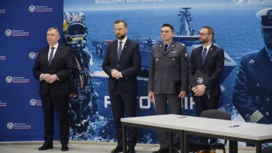 Polish defense ministry and industry leaders standing in front of the Polish Navy's Ratownik rescue ship concept design