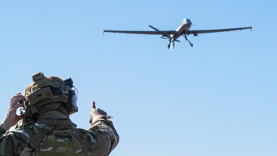 A US Air Force Airman assigned to the 1st Special Operations Support Squadron Mission Sustainment Team watches as an MQ-9 Reaper prepares to land on an unprepared dirt surface