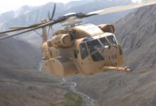 A single CH-53K helicopter flying in between mountains