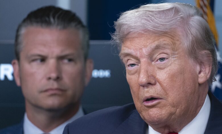 President Donald Trump speaks to reporters as Defense Secretary Pete Hegseth stands behind him