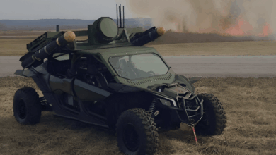 V2X's Tempest vehicle parked on a grassland with burning fires in the background