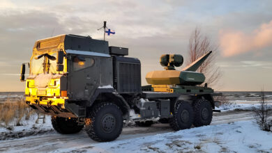 A Finnish Army military truck fitted with the Skyspotter counter-drone system, shown during a winter field test near a coastline, with the Skyspotter sensor mast and turret mounted on the rear platform under low evening light