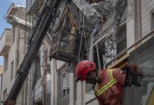 Iranian firefighters work to recover the body of an Afghan woman from the ruins of a residential building in Tehran, Iran, on March 27, 2026.
