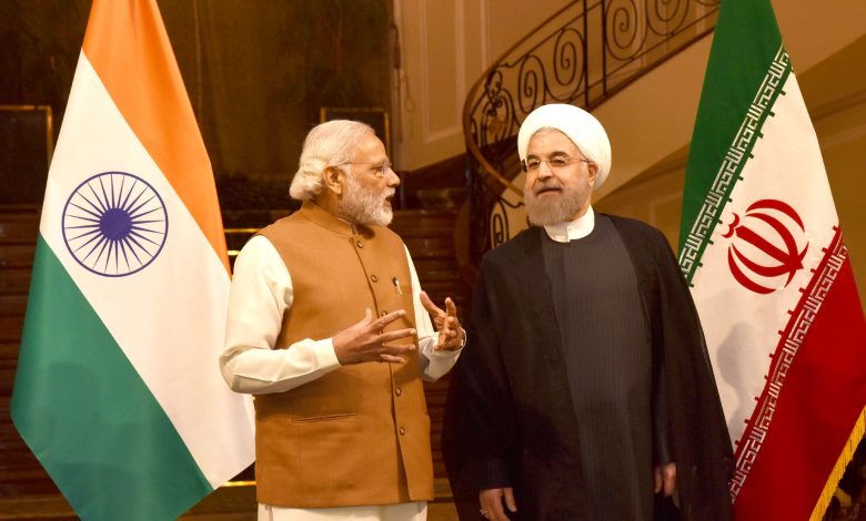 Narendra Modi shaking hands with Iranian President Hassan Rouhani with Indian and Iranian flags behind them.