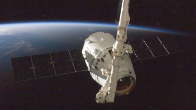 A SpaceX Dragon spacecraft orbits Earth with its solar arrays deployed.