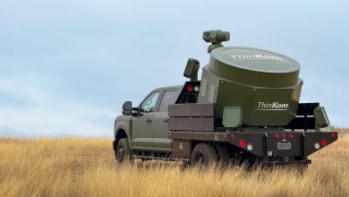 A matte-green flatbed truck with the ThinKom Alecto high-power microwave system mounted in the bed.