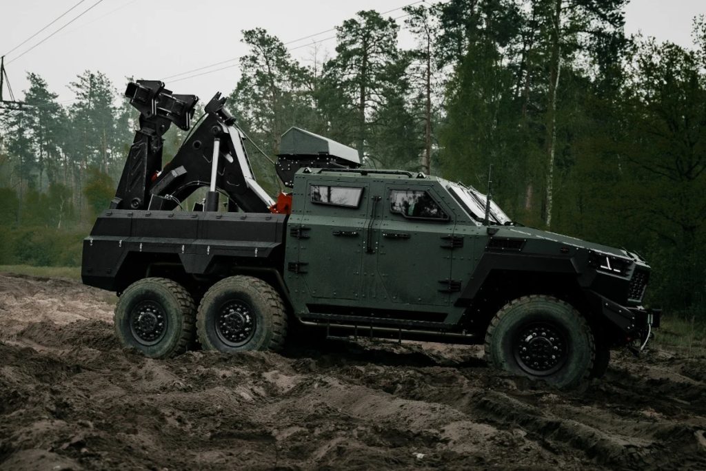 Inguar 4 military recovery vehicle with a rear-mounted lifting crane traversing muddy off-road terrain, designed for frontline equipment rescue operations