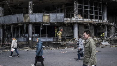 People are walking in front of a destroyed shopping mall in Liukanivka district in Kyiv.